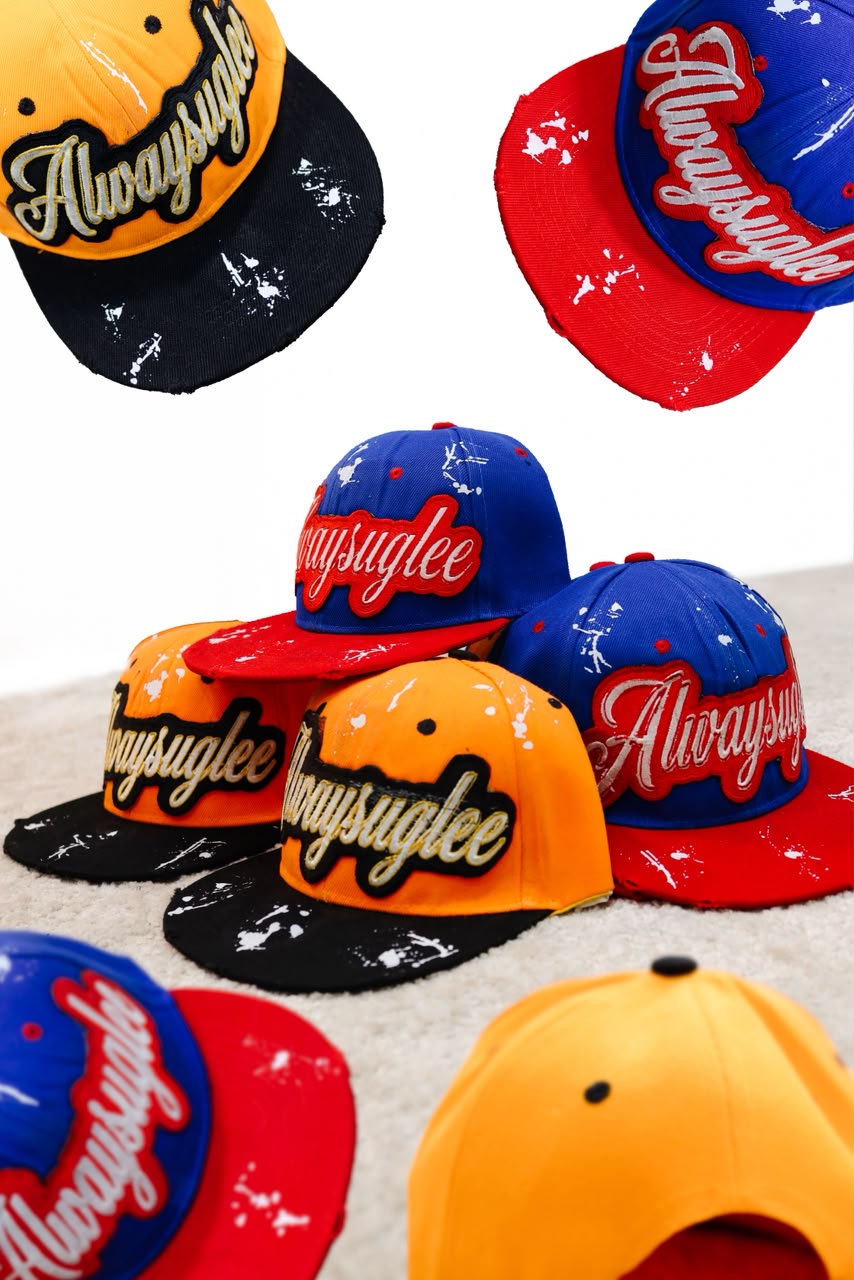 Orange and blue snapback caps with embroidered script patches and paint splatter